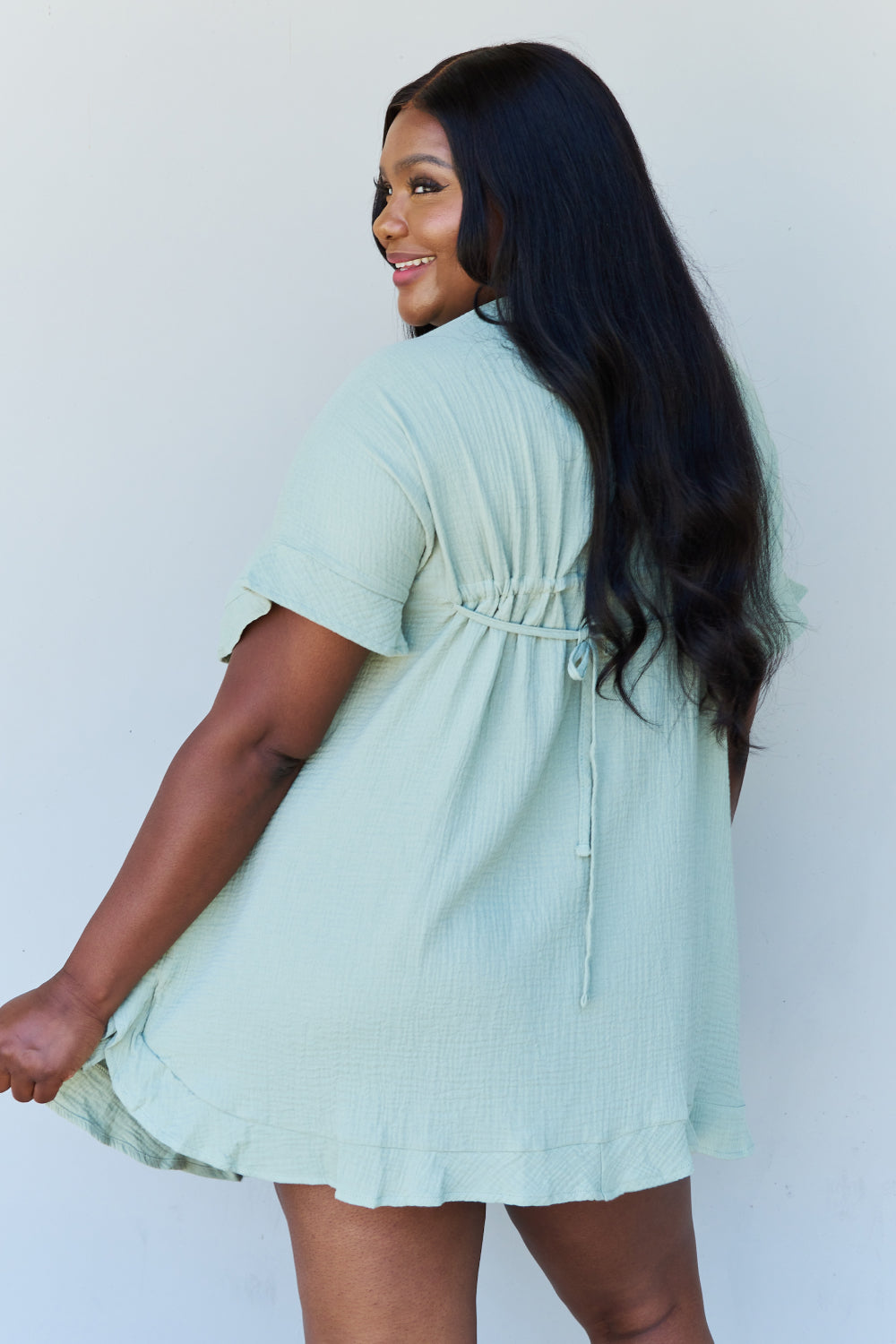 Back view of model wearing plus size ruffle hem dress with drawstring waistband