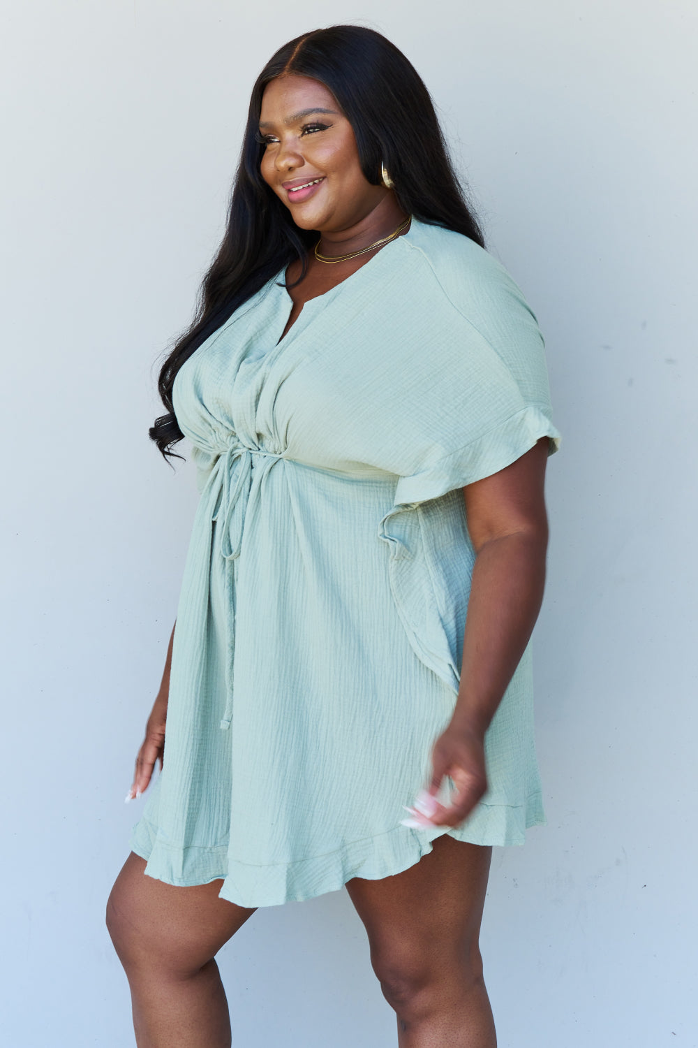 Side view of model wearing plus size ruffle hem dress with drawstring waistband