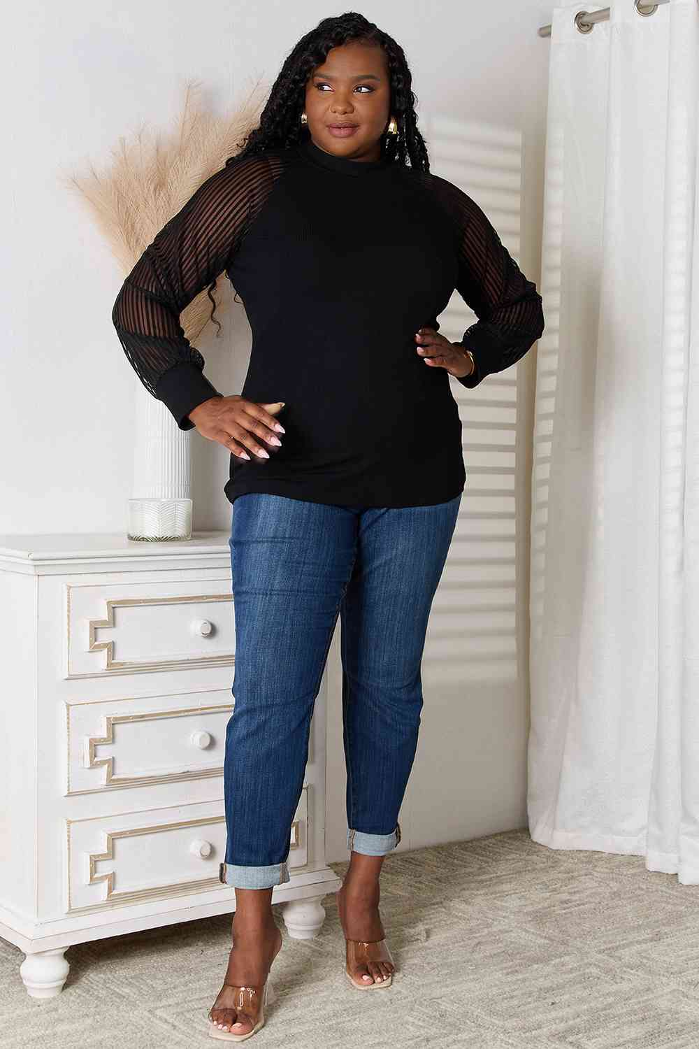 Model is wearing plus size sheer long sleeve black blouse