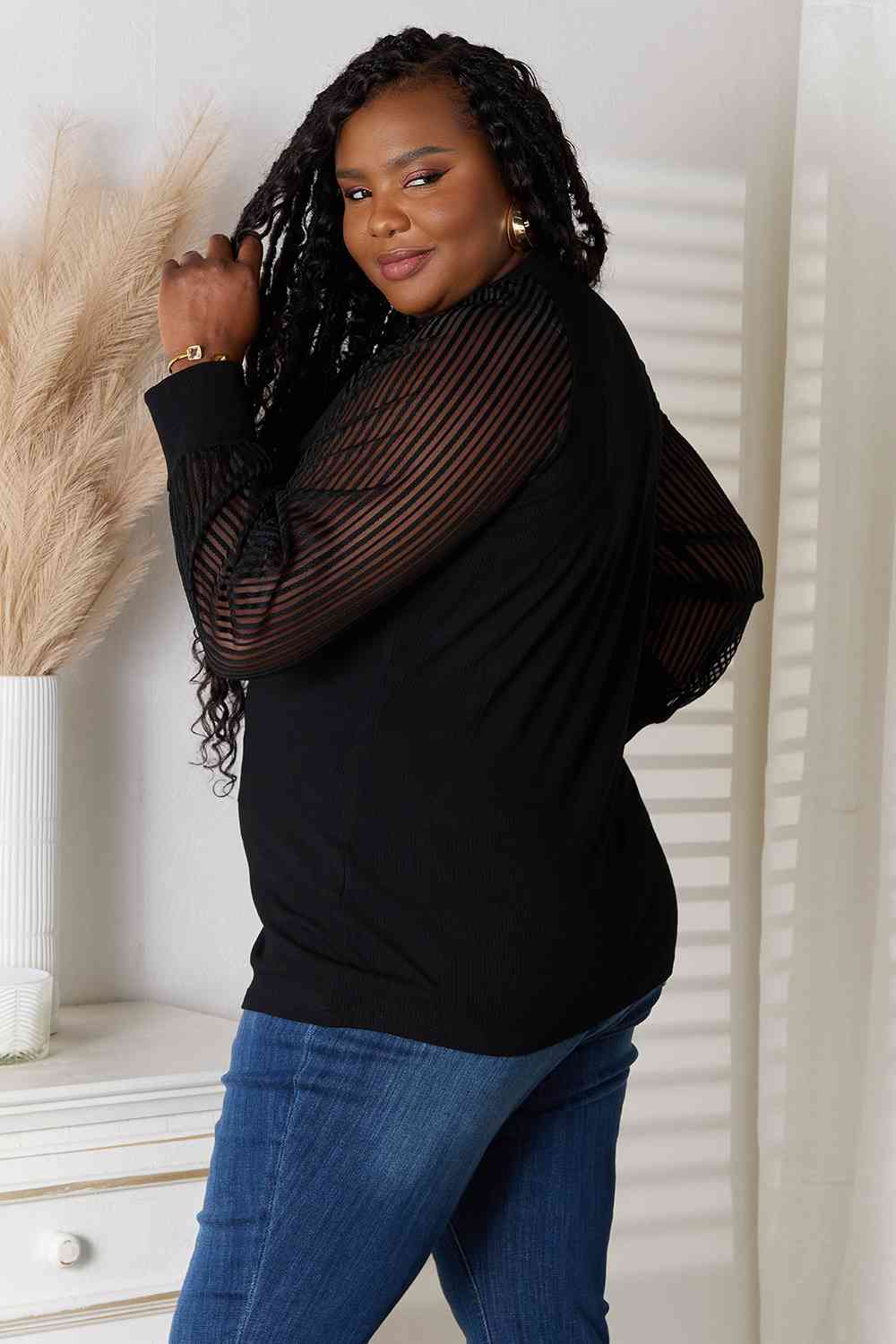 side view of model wearing plus size sheer long sleeve black blouse