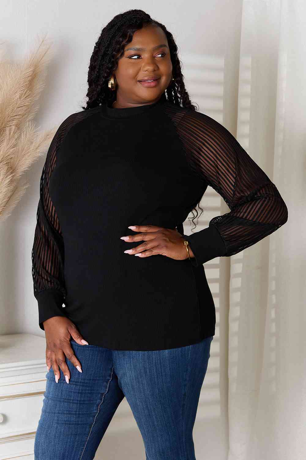 left facing view of model wearing sheer long sleeve black blouse  