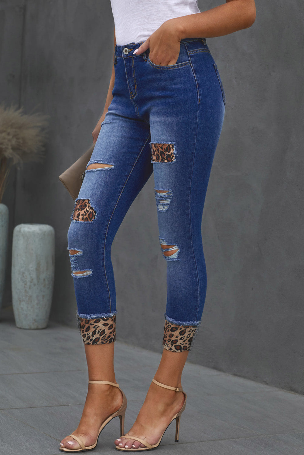 Left side view of model wearing Leopard Print Denim. These jeans are cropped and distressed.