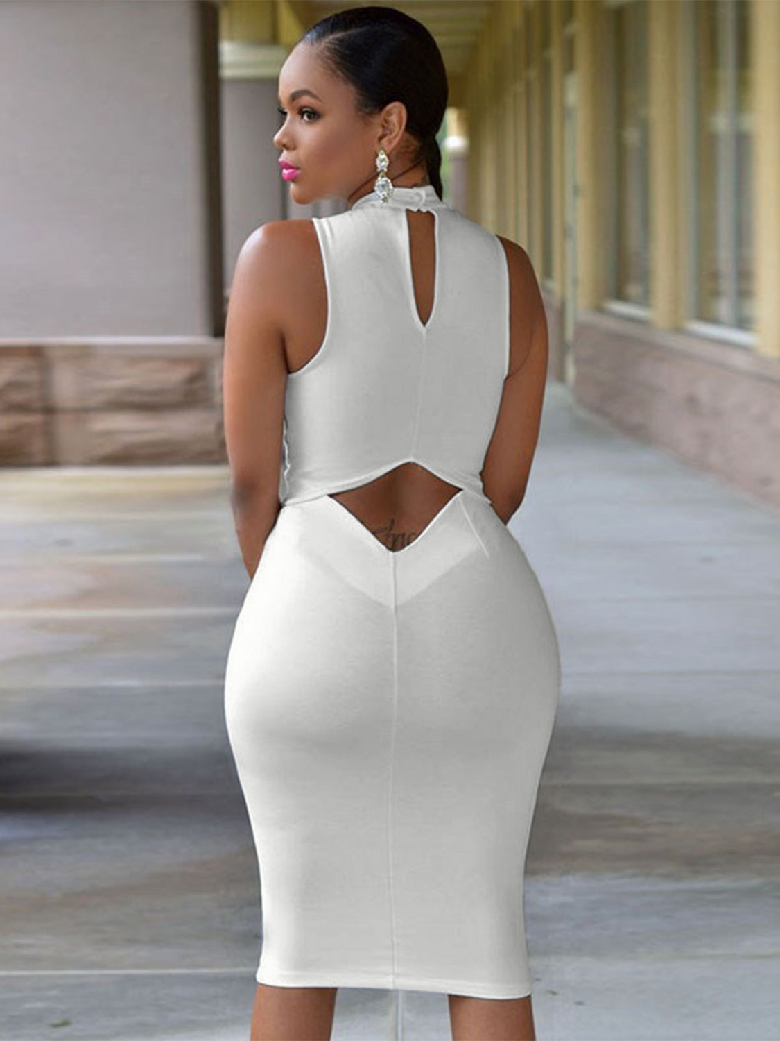 Back view of model wearing Mock Neck Sleeveless Dress with cutout small of back in white 