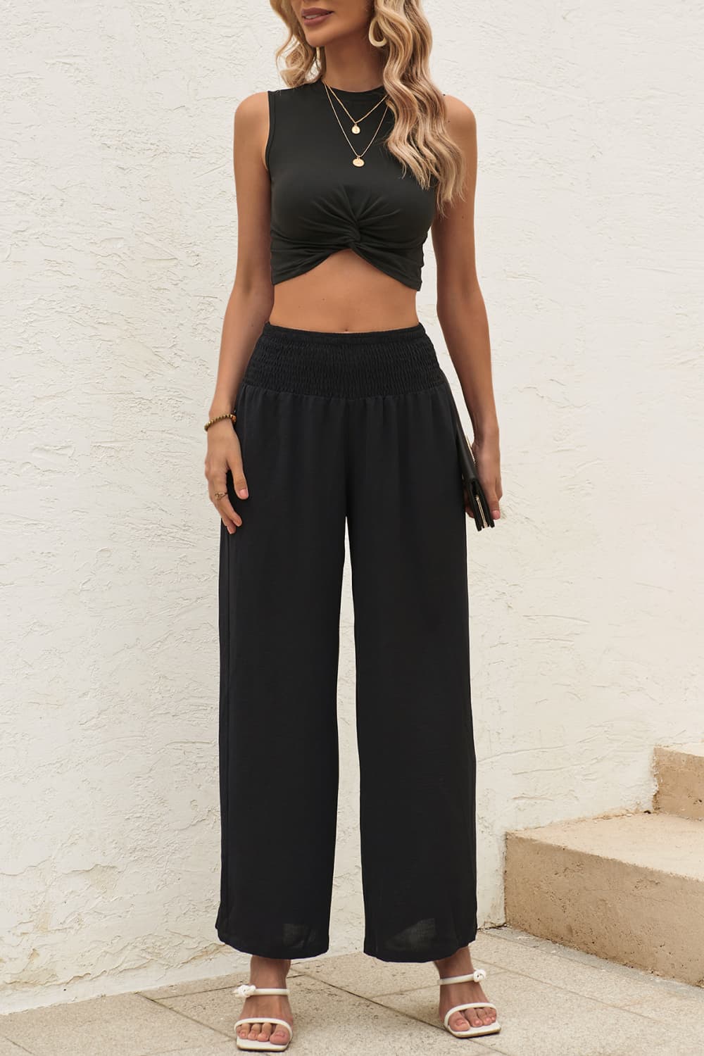 Front view of model wearing two piece crop top pants set in the color black