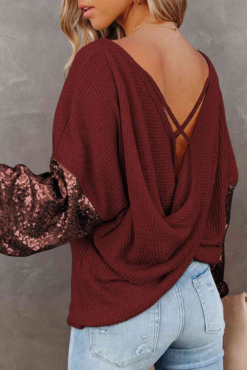 Back view of model wearing sequin sleeve waffle knit blouse in the color wine