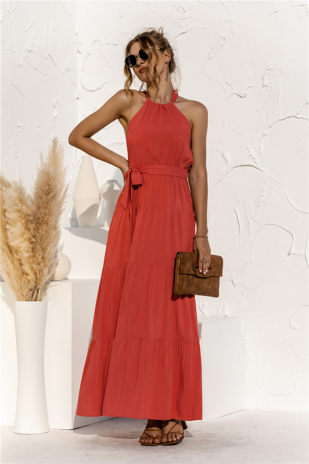 Model is wearing orange halter neck maxi dress with tie front waist in the color orange.